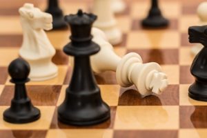 Une reine noire d'un jeu d'échecs surplombe une reine blanche à terre