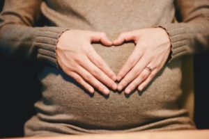 Une personne enceinte forme un coeur avec ses mains autour de son ventre