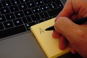 Une personne prend des notes sur un post-it