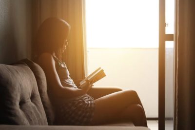 [Image d'illustration]Une femme installée confortablement sur un canapé lit un livre
